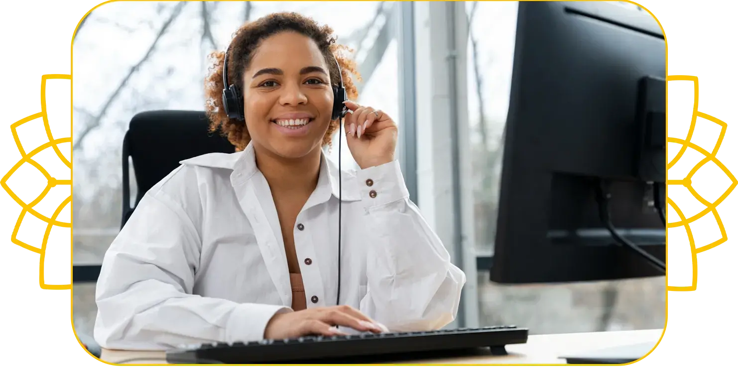 Mulher negra sorrindo com fone de ouvido em frente ao computador realizando atendimentos