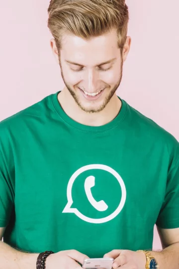 Homem segurando celular com uma camisa com ícone do aplicativo WhatsApp